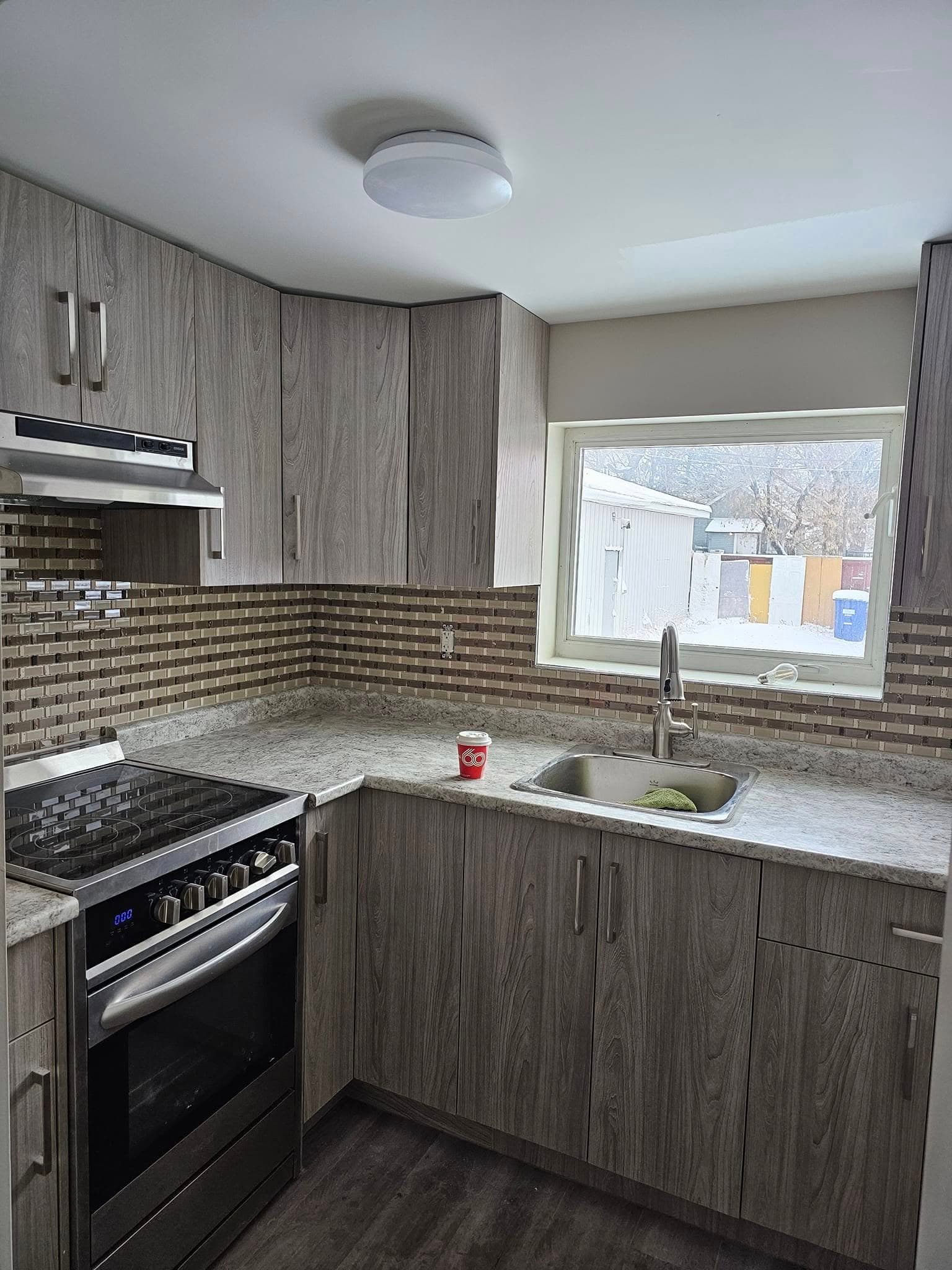 Renovated kitchen with grey cabinets, tile backsplash and new appliances