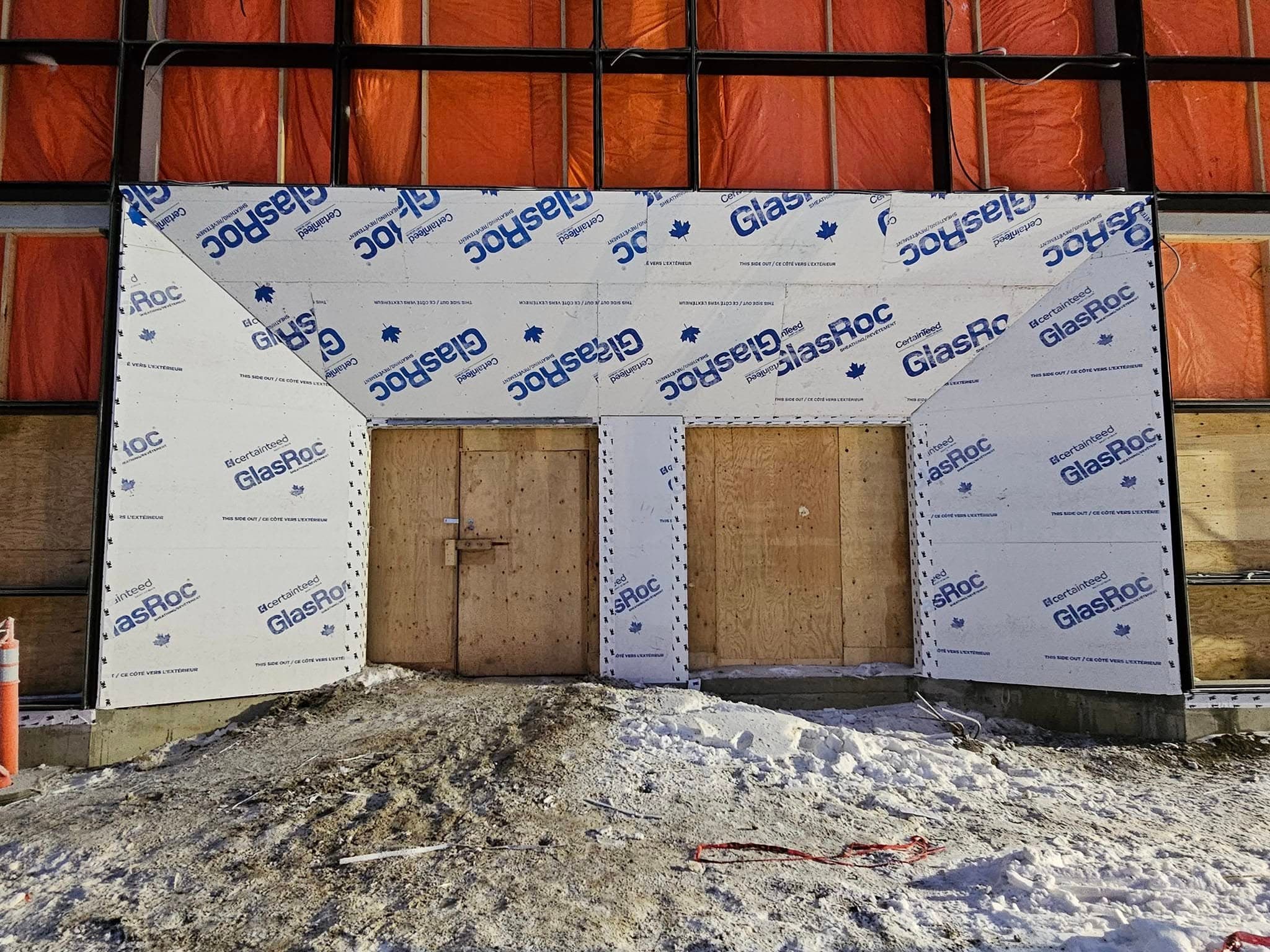 Exterior wall sheathing installed around double doors in winter