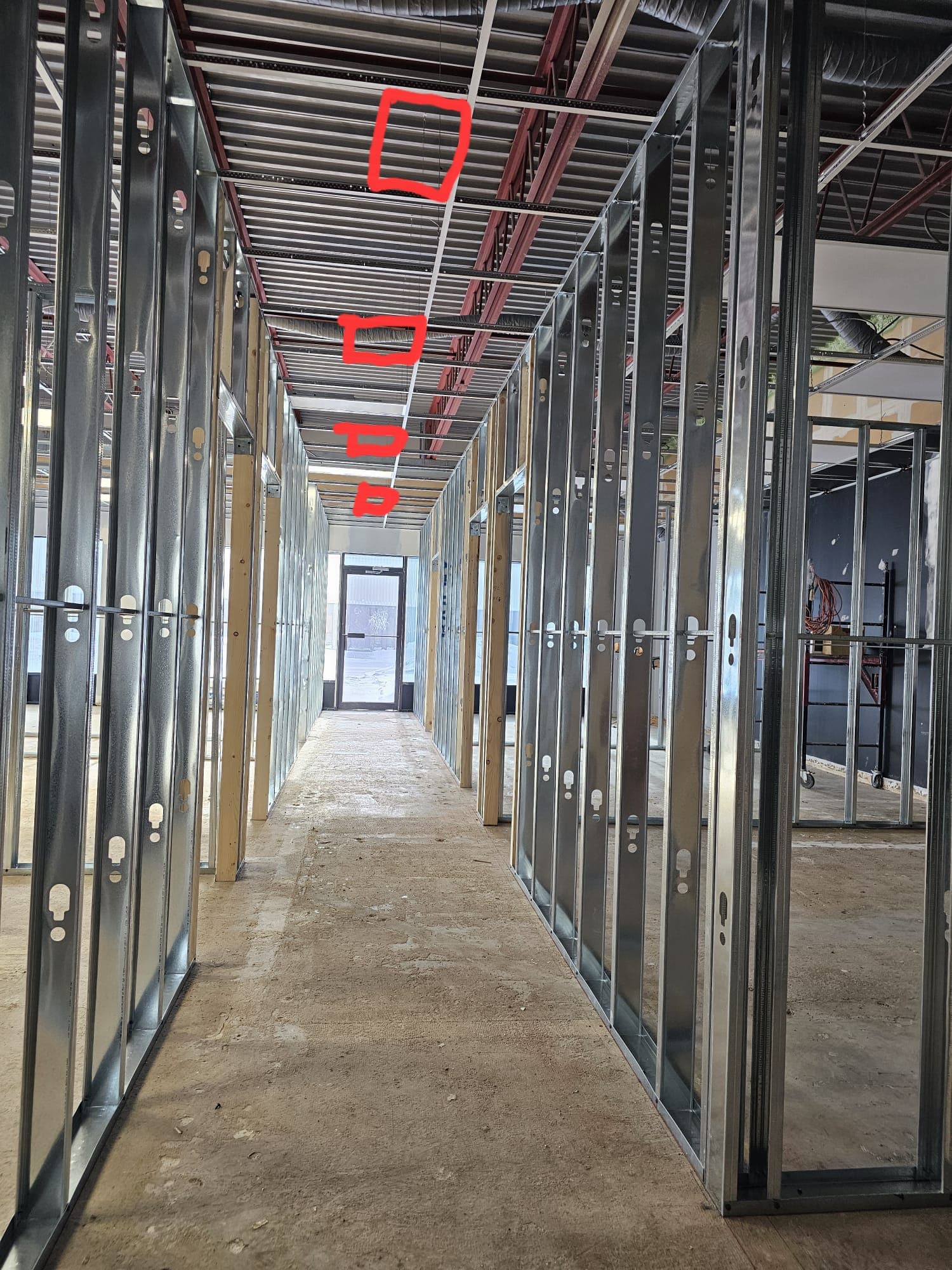 Steel stud framing along a commercial corridor with exposed ductwork