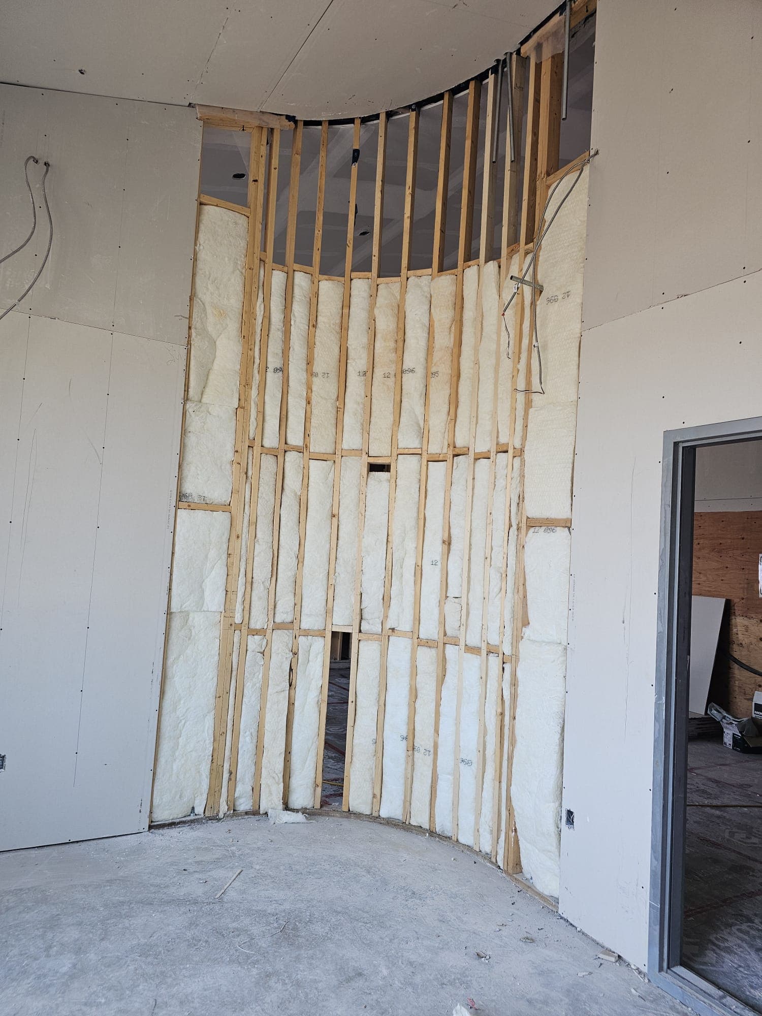 Curved wall framing with insulation before boarding