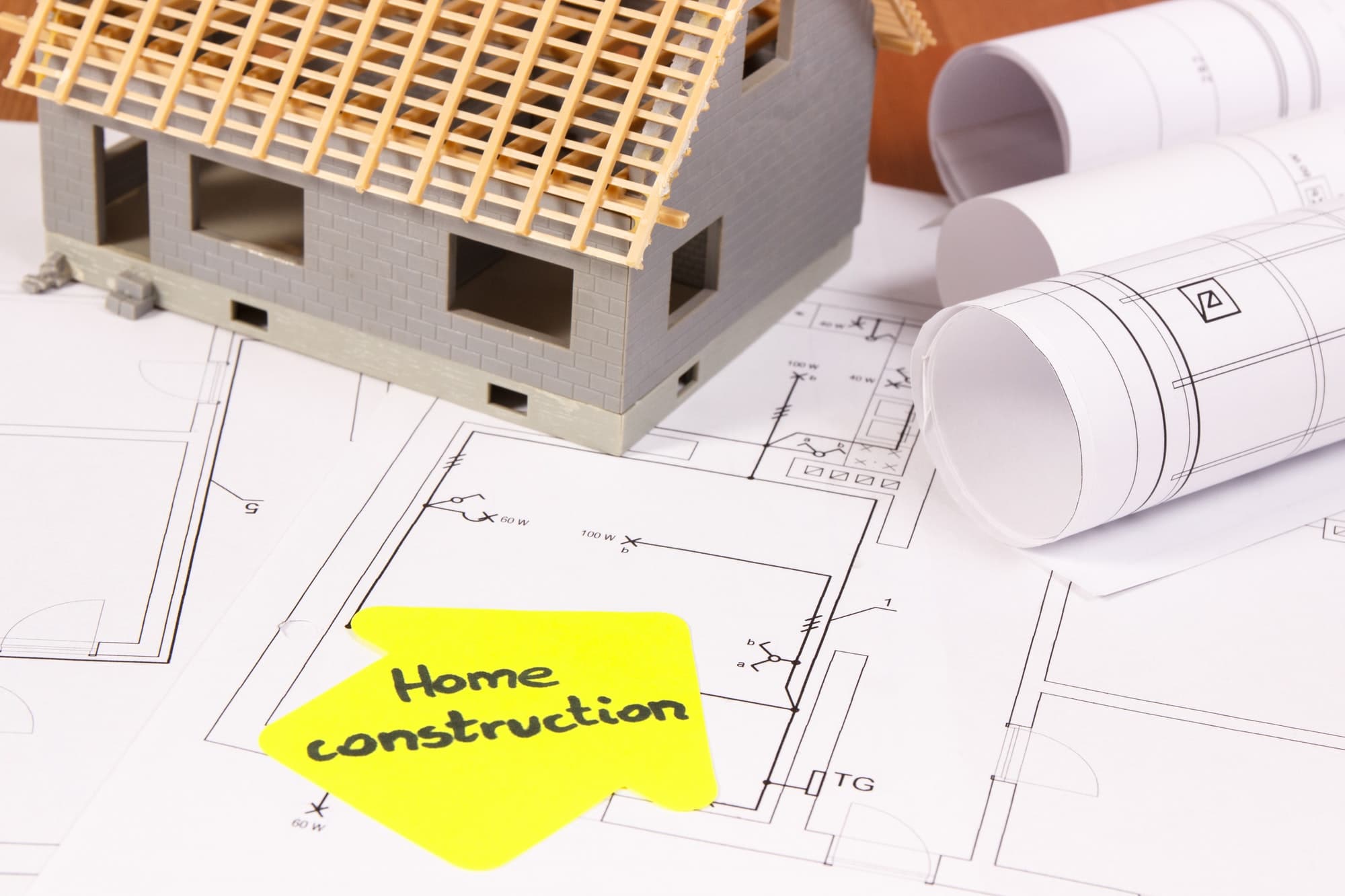 Model house and rolled blueprints on a construction floor plan
