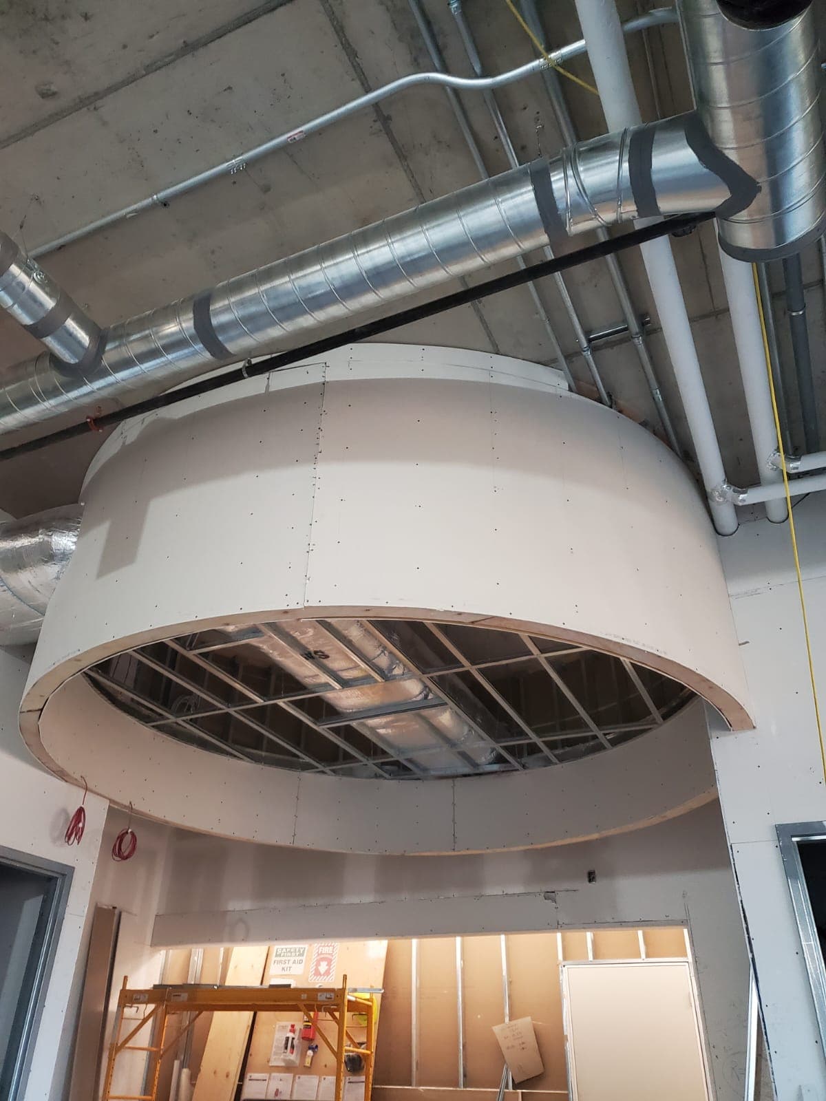 Large circular drywall bulkhead below exposed ductwork